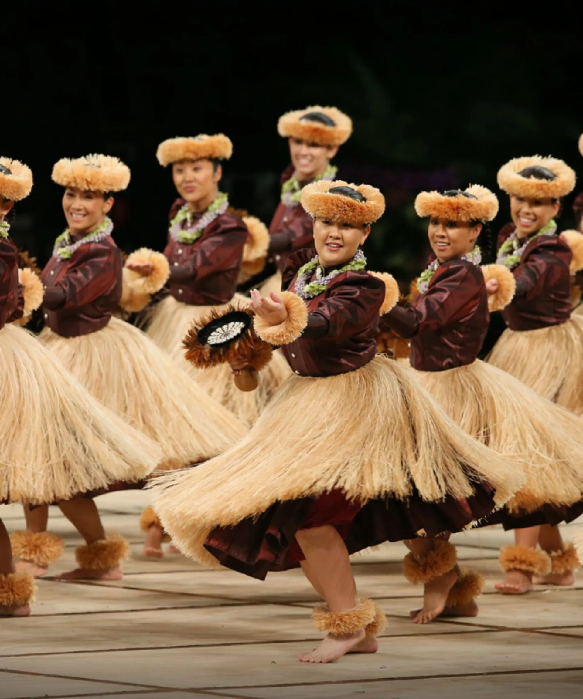 Hula dancers in traditional attire perform on stage.